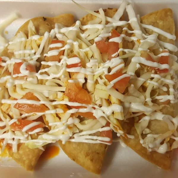 Three crispy tacos from Taco Depot, topped with shredded cheese, diced tomatoes, and sour cream.