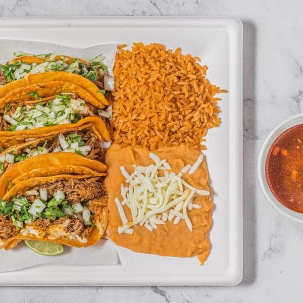 Taco Depot's birria tacos with rice, refried beans, and a side of consommé on a white tray.